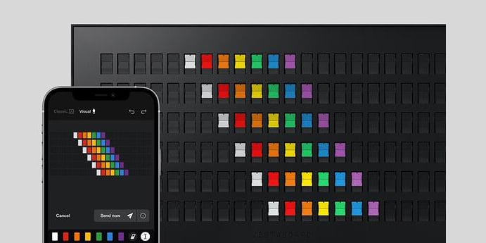 Vestaboard smart messaging display showing rainbow pattern and app visual editor